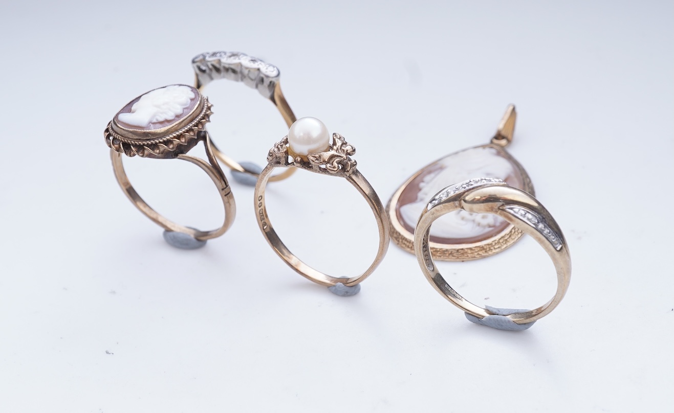A collection of four rings and a pendant